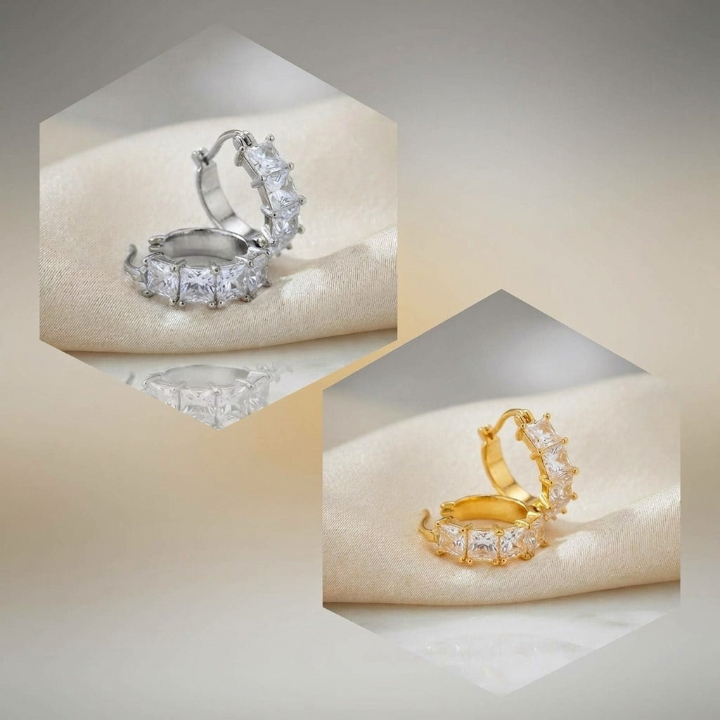 Two small hoop-style rings with clear rectangular stones, shown in silver and gold metal finishes on a soft cream fabric surface inside hexagonal frames.