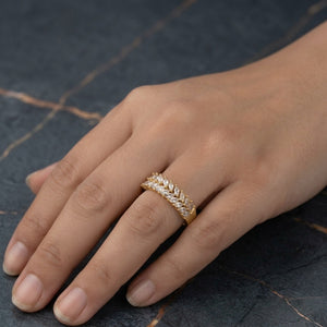 A close-up of a hand wearing a gold ring with pavé-set clear stones, resting on a dark marble surface.