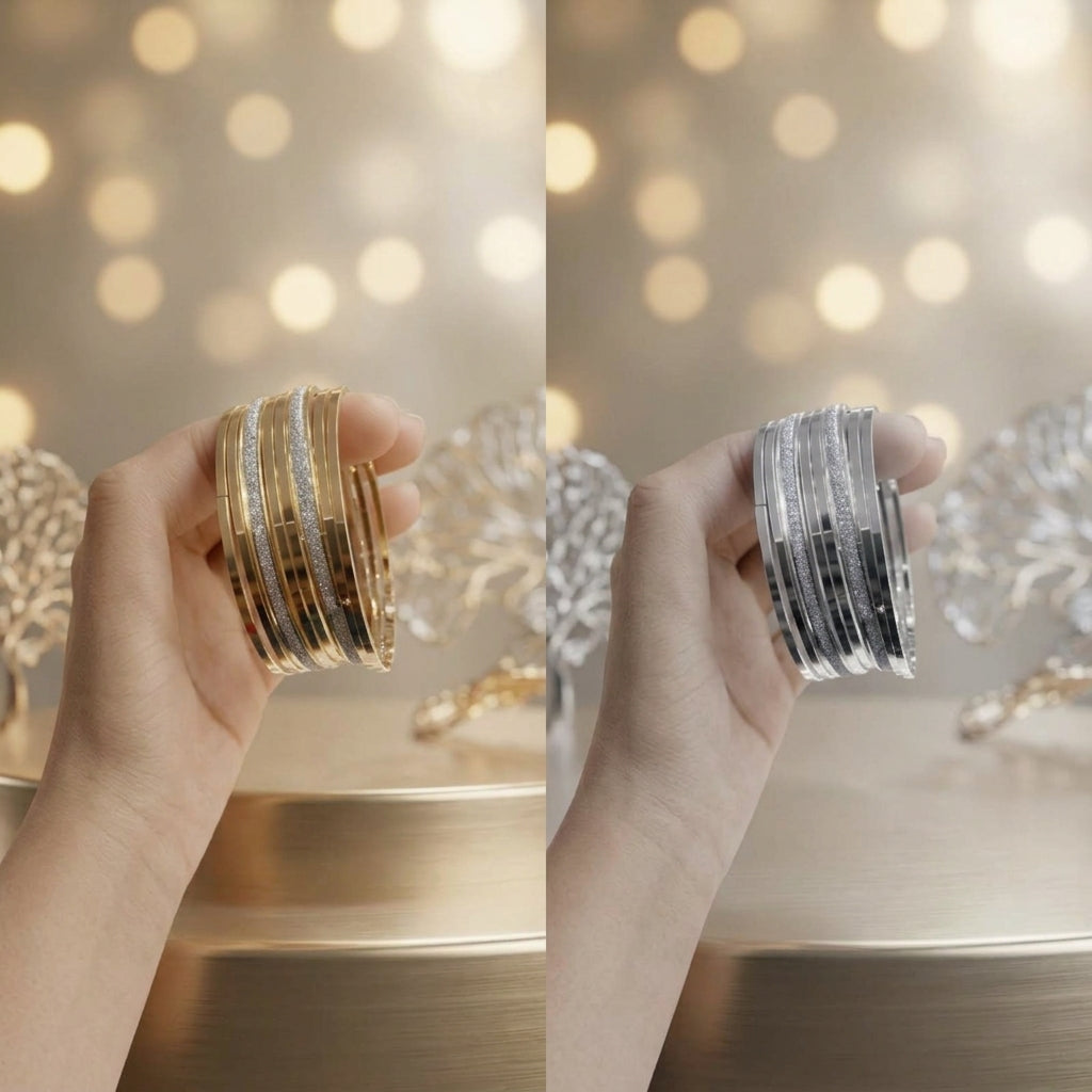 A hand holds a stack of slim metallic bangles in two color variants: one with gold, silver, and white stripes, and the other with silver and black stripes. The background features a warm bokeh light effect and decorative crystal ornaments.